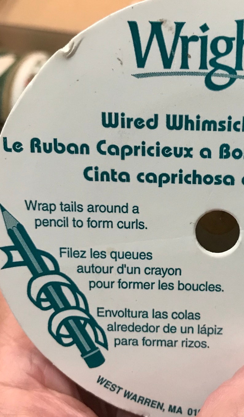 May include: A white spool of Wrights Wired Whimsical ribbon. The label includes instructions in English, French, and Spanish, with a pencil graphic. The text advises wrapping the ribbon around a pencil to form curls.