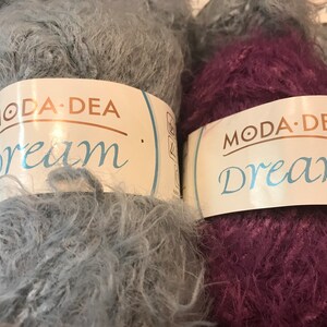 May include: Two skeins of yarn, one gray and one purple, with the label "Moda Dea Dream" on each.