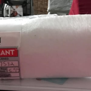 May include: A white fabric remnant from Joann Fabrics and Crafts store. The label reads "Fabric Remnant" and has a price tag with the number "01471538".