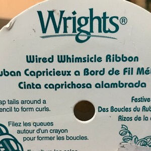 May include: A spool of Wrights Wired Whimsicle Ribbon. The label is white with teal text that reads "Wired Whimsicle Ribbon" and instructions for curling the ribbon. The ribbon is designed for festive occasions.