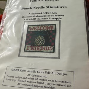 May include: A clear plastic package containing a punch needle miniature craft kit titled Karen Amadio Gates Folk Art Designs Punch Needle Miniatures #MK-109 Welcome Pineapple. The insert shows a square needlework design of a pineapple with the text WELCOME and FRIENDS.
