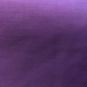 May include: Solid purple fabric with a subtle sheen. The fabric has a smooth texture and a deep, rich color, with slight variations in tone across the surface. The overall appearance is of a luxurious material.