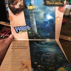 May include: A panoramic jigsaw puzzle featuring the art of David Miller. The puzzle depicts a lighthouse on a rocky shore with a stormy sky and lightning. The puzzle box also features a starfish and a piece of the puzzle.