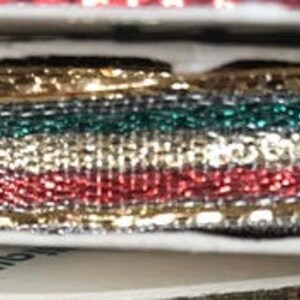 May include: Spools of decorative ribbon in various colors, including gold, red, green, and blue. The ribbon has a metallic sheen and a woven texture. The spools are stacked on top of each other, showing the different colors and textures.