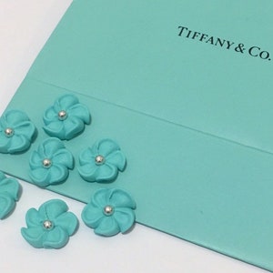 100 teal royal icing flowers Approx.size 1/2” with silver sugar center
