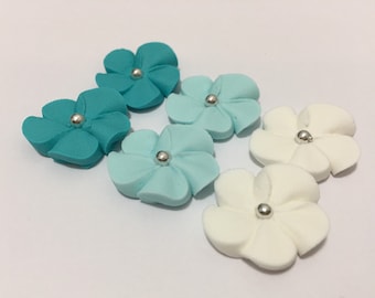 100 royal icing flowers (white and two shades of teal) Approx. size 3/4” with silver sugar center