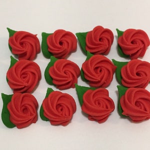 May include: A dozen red sugar roses with green leaves. The roses are arranged in rows on a white surface.