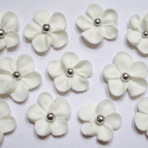 100 white royal icing flowers Approx. size 3/4” with silver sugar center.