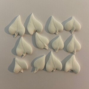 May include: A collection of 15 white sugar paste leaves, shaped like hearts, for decorating cakes or cupcakes.