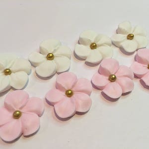 100 royal icing flowers ( 50 white and 50 pink) Approx. size 3/4” with gold sugar center