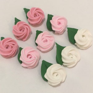 May include: Eight sugar paste rose decorations, four in pink and four in white, with green leaves. The roses are in a swirl design.