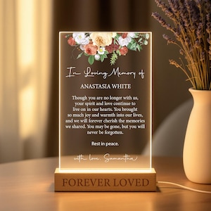 May include: A white illuminated acrylic plaque with a floral design and the text "In Loving Memory of Anastasia White" and a message about remembering a loved one. The plaque is on a wooden base with the text "Forever Loved".