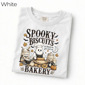Pode incluir: Uma t-shirt branca com um gráfico de um fantasma com chapéu de chef e avental, a estender massa com um rolo. O texto diz SPOOKY BISCUITS we knead em, you need em BAKERY, rodeado por farinha, açúcar, morcegos, folhas e uma abóbora.