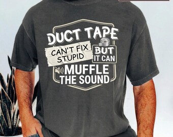 Peut inclure: Un t-shirt à manches courtes gris anthracite avec un motif graphique blanc portant le texte "DUCT TAPE CAN'T FIX STUPID BUT IT CAN MUFFLE THE SOUND" et une petite illustration d'un rouleau de ruban adhésif. Le t-shirt est étiqueté Comfort Colors Pepper.