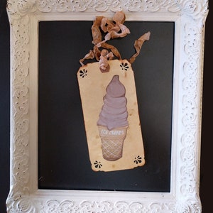 May include: A vintage-style tag with a hand-painted illustration of a purple ice cream cone. The tag is tied with a brown ribbon and has the words "ICE CREAM" written on it.