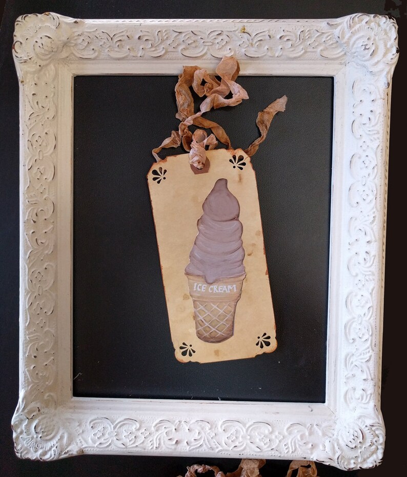 May include: A vintage-style tag with a hand-painted illustration of a purple ice cream cone. The tag is tied with a brown ribbon and has the words "ICE CREAM" written on it.