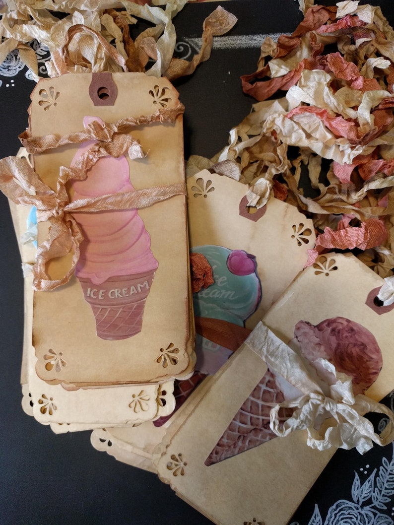 May include: A stack of brown paper gift tags with a scalloped edge. Each tag features a different ice cream cone design with the words "ICE CREAM" printed on one tag. The tags are tied with white and brown ribbon.