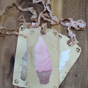 May include: Three vintage-style gift tags with a scalloped edge. The center tag features a pink and white ice cream cone with the text "ICE CREAM". The tag on the left has a brown and white ice cream cone with the text "ICE". The tag on the right has a white ice cream cone.