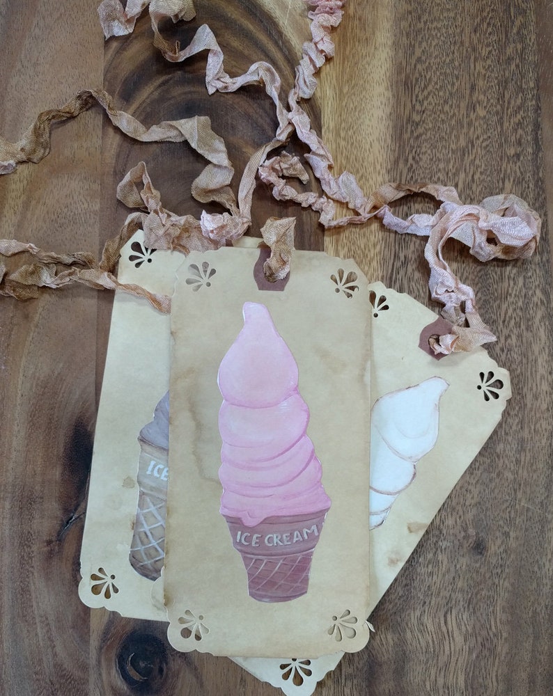 May include: Three vintage-style gift tags with a scalloped edge. The center tag features a pink and white ice cream cone with the text "ICE CREAM". The tag on the left has a brown and white ice cream cone with the text "ICE". The tag on the right has a white ice cream cone.