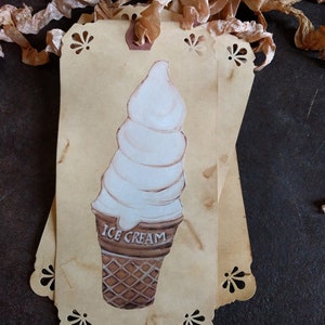 May include: A vintage-style tag with a hand-painted illustration of a white ice cream cone on a brown background. The tag has a scalloped edge and the words "ICE CREAM" are printed on the cone.
