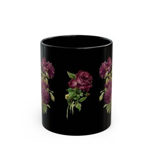 May include: A black ceramic mug featuring a repeating botanical illustration of deep burgundy roses with green leaves. The floral design is printed vertically on the exterior surface of the cylindrical vessel, showcasing dark red petals and stems.