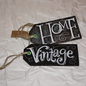 May include: Two black chalkboard tags with white chalk lettering. The top tag says "HOME" and the bottom tag says "Vintage".