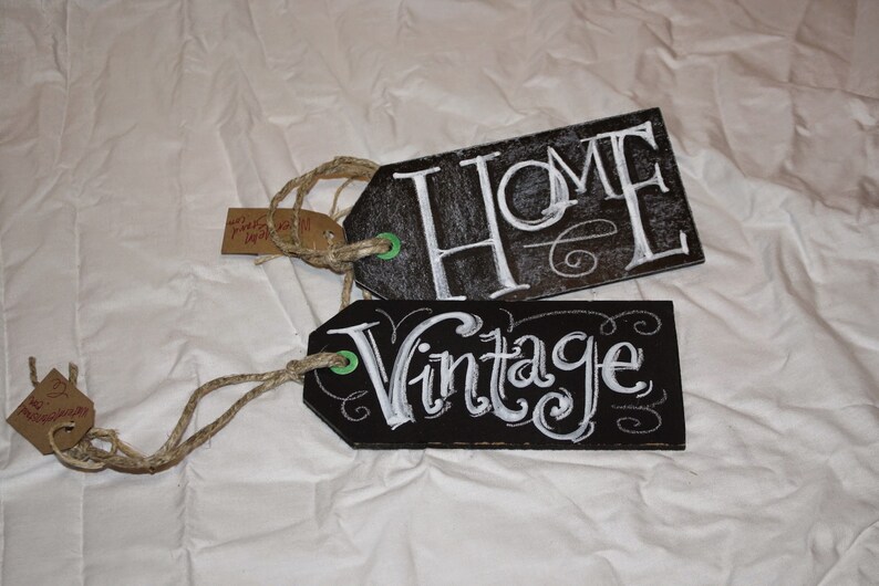 May include: Two black chalkboard tags with white chalk lettering. The top tag says "HOME" and the bottom tag says "Vintage".