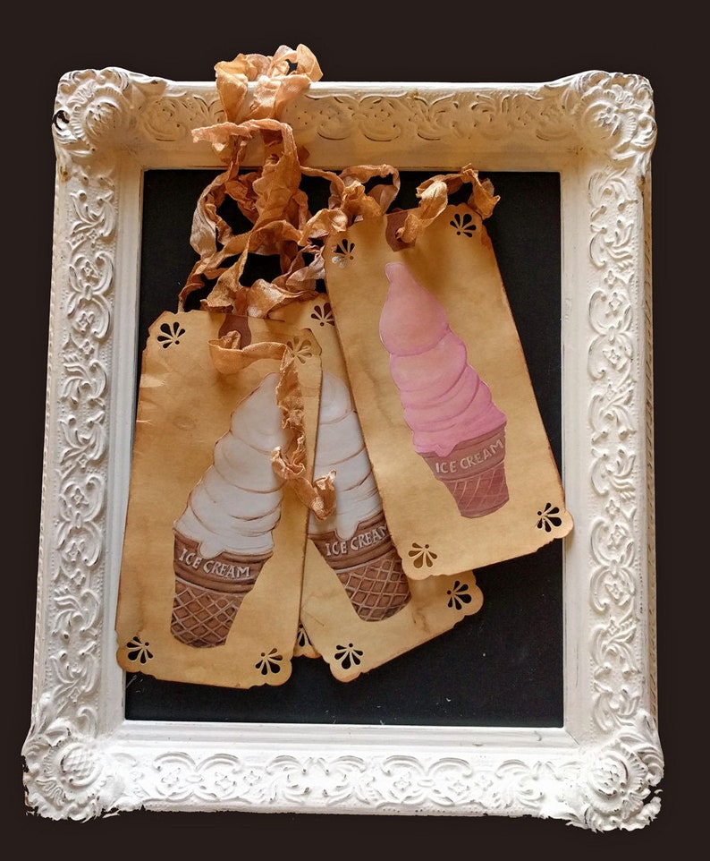 May include: Three vintage ice cream cone tags with a white frame. The tags are made of brown paper with a scalloped edge and feature illustrations of ice cream cones with the words "Ice Cream" printed on them.