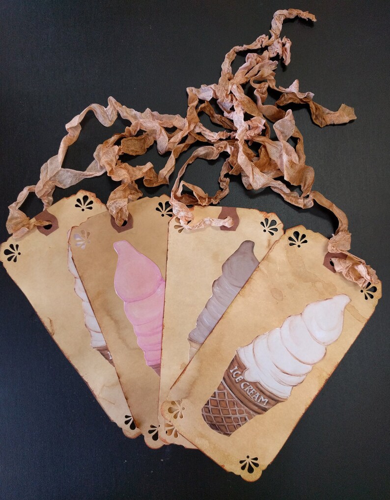 May include: Five brown paper tags with scalloped edges and a lace ribbon. Each tag features a different ice cream cone illustration. The text "ICE CREAM" is printed on one of the tags.