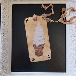 May include: A vintage-style tag with a hand-drawn illustration of an ice cream cone. The tag is made of brown paper and has a white background. The ice cream cone is white with a brown waffle cone. The tag is tied with a brown ribbon and has the words "ICE CREAM" printed on it.