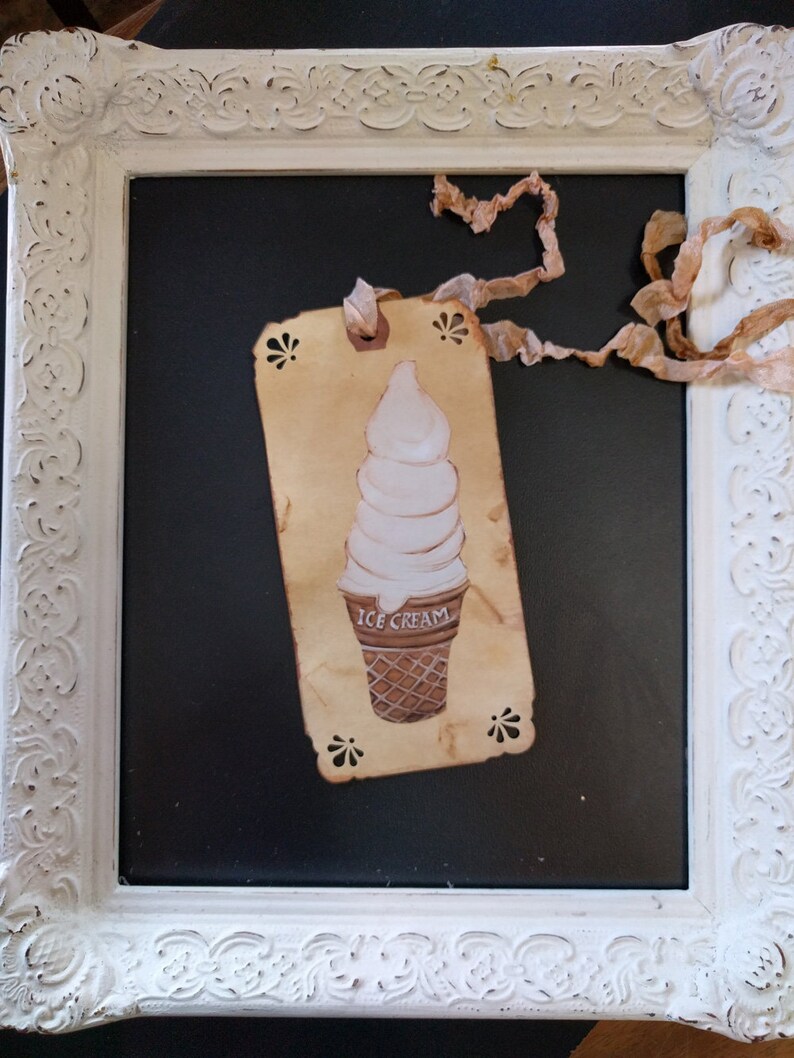 May include: A vintage-style tag with a hand-drawn illustration of an ice cream cone. The tag is made of brown paper and has a white background. The ice cream cone is white with a brown waffle cone. The tag is tied with a brown ribbon and has the words "ICE CREAM" printed on it.