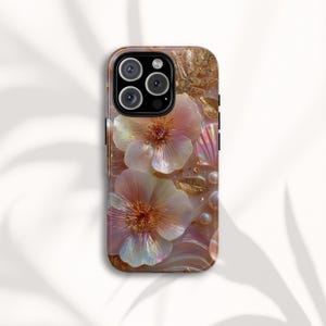 May include: A decorative phone case featuring a floral design with iridescent petals and gold accents. The case has a pearlescent finish with embedded seashells and pearls. The camera lenses are visible at the top.