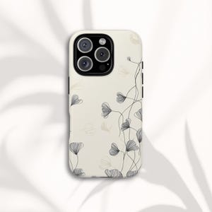May include: A cream-colored phone case featuring a delicate floral design. Black line art depicts stylized flowers and vines across the surface. The case has a glossy finish and a camera cutout.