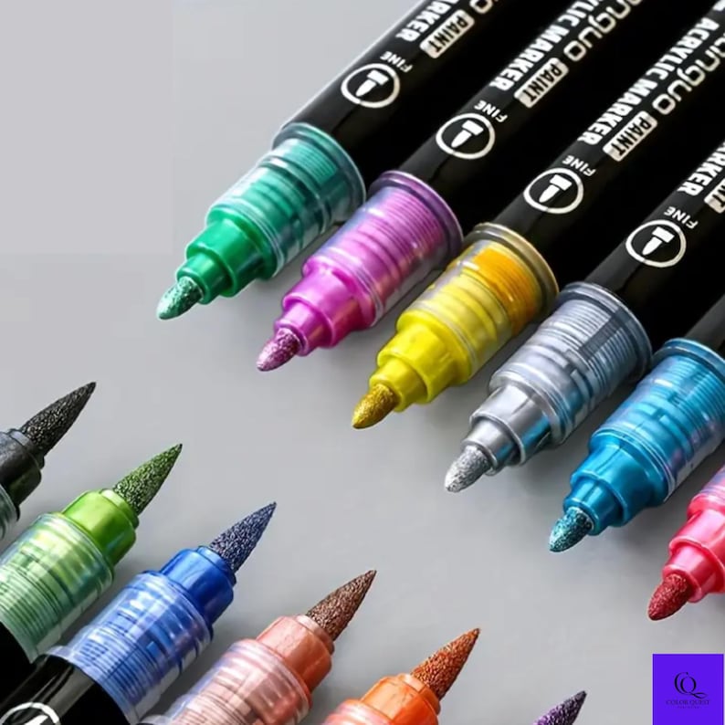 May include: A collection of metallic acrylic paint markers in various colors, including green, pink, yellow, silver, and blue. The markers have black barrels with white text and fine tips, ideal for art projects and crafts.