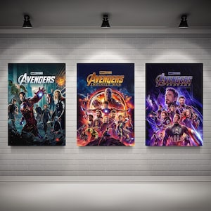 Puede incluir: Tres carteles de películas con los Vengadores. El primer cartel es rojo y azul con el texto "Avengers". El segundo cartel es morado y dorado con el texto "Avengers Infinity War". El tercer cartel es morado y azul con el texto "Avengers Endgame".