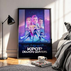 May include: Framed poster featuring the title "KPOP DEMON HUNTERS" with stylized illustrations of female characters in action poses. The artwork has a futuristic, neon-lit cityscape backdrop, with a color palette of purple, blue, and pink.