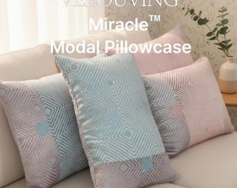 May include: Four decorative Modal pillowcases in shades of blue, pink, and gray, arranged on a cream-colored sofa. The pillowcases feature a geometric diamond pattern. The text "VELOUVING Miracle Modal Pillowcase" is visible.