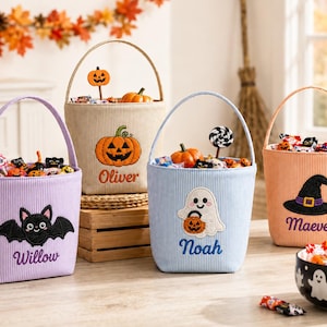 Puede incluir: Cuatro cubos de Halloween de pana en colores lavanda, beige, azul claro y naranja. Cada cubo presenta un personaje bordado: un murciélago con el nombre Willow, una calabaza con Oliver, un fantasma con Noah y un sombrero de bruja con Maeve.