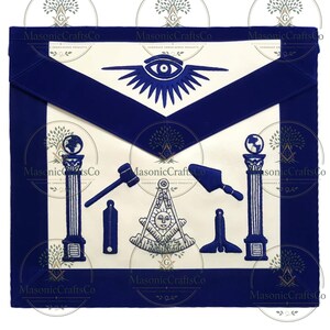 Puede incluir: Delantal masónico blanco y azul marino con símbolos bordados. El delantal presenta un diseño de ojo, pilares y otros emblemas. El texto "Masonic CraftsCo" es visible. El delantal es rectangular con un borde azul marino.