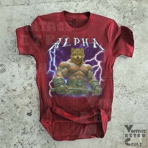 May include: Red t-shirt with a graphic of a muscular wolf with lightning bolts and the word "ALPHA" printed on the front.