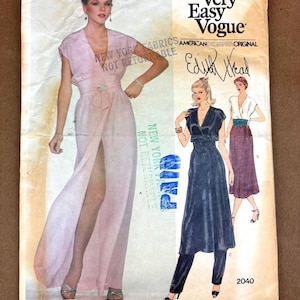 May include: Vintage Very Easy Vogue sewing pattern featuring a pink dress with a high slit and a wrap-style bodice. The pattern includes designs by Edith Head, with the number 2040 visible.