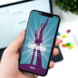 以下が含まれることがあります： スマートフォンには、「Confidence」というタイトルの本の表紙が表示されています。スーツを着た男性のグラフィックが描かれています。背景はターコイズブルーで、放射線状の線があります。著者の名前、Philip Wayは一番下にあります。