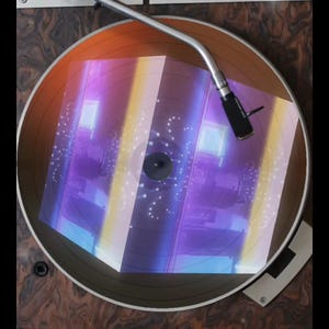 May include: A vintage record player with a turntable and a tonearm. The turntable is playing a record with a holographic design that appears to be a cube with a purple, blue, and yellow color scheme.