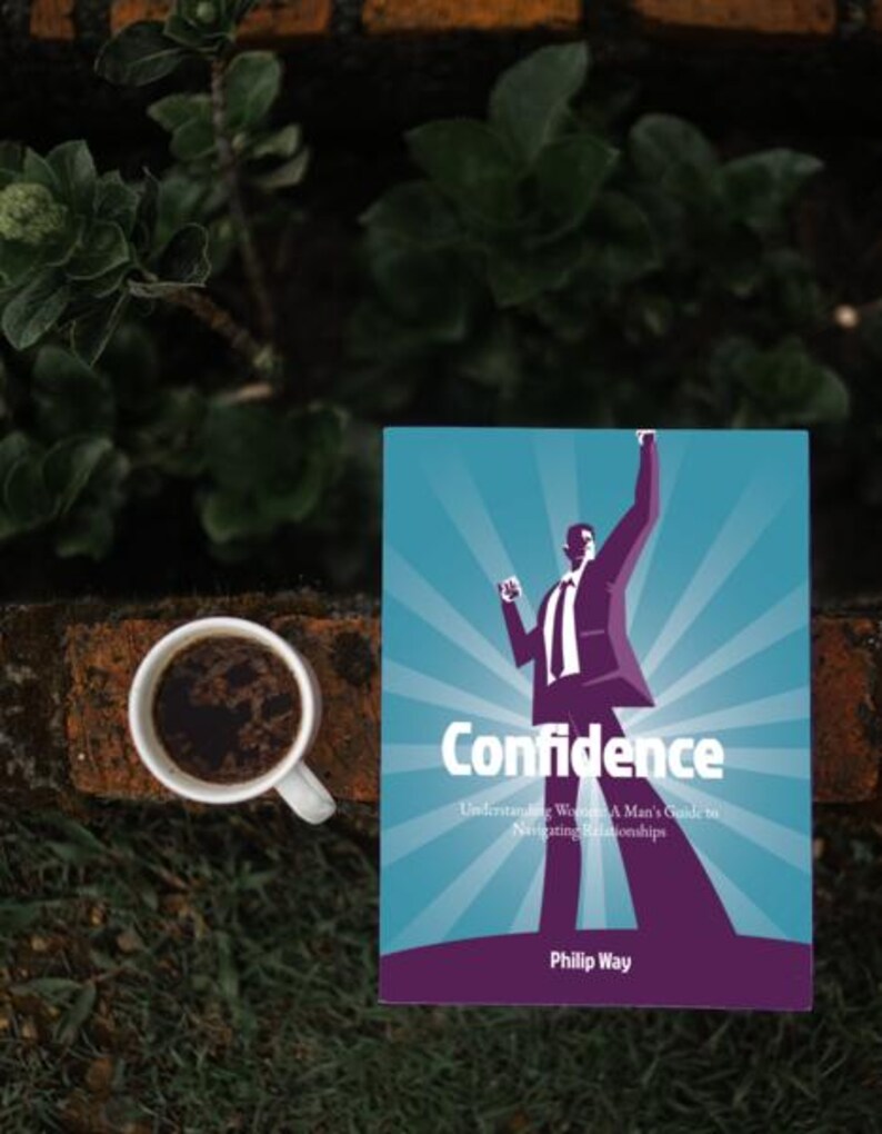 以下が含まれることがあります： 「Confidence」というタイトルの本。ターコイズ色の表紙にスーツ姿の男性のグラフィック。本の隣には、濃いコーヒーが入った白いコーヒーカップがあります。背景には緑とレンガの壁があります。