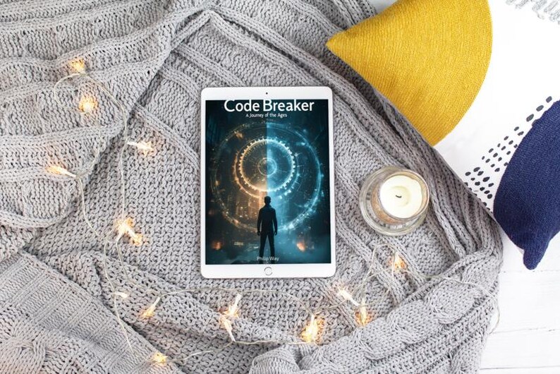 May include: A tablet displaying the book cover of "Code Breaker: A Journey of the Ages" rests on a gray knitted blanket. A yellow pillow, a candle in a glass holder, and a decorative pillow with blue accents are also present. String lights are draped across the blanket.