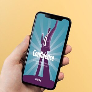 以下が含まれることがあります： スマートフォンには、「Confidence」というタイトルの本の表紙が表示されています。表紙には、腕を上げたスーツ姿の人物が、放射線状のラインが入ったターコイズブルーの背景に描かれています。著者の名前、Philip Wayは下部に表示されています。