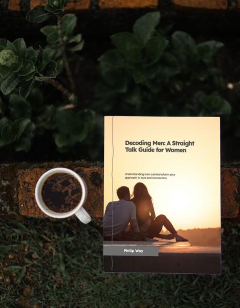 May include: A book titled "Decoding Men: A Straight Talk Guide for Women" with a cover image of a couple at sunset. A white coffee cup filled with dark liquid sits to the left of the book, with a background of greenery and brick.