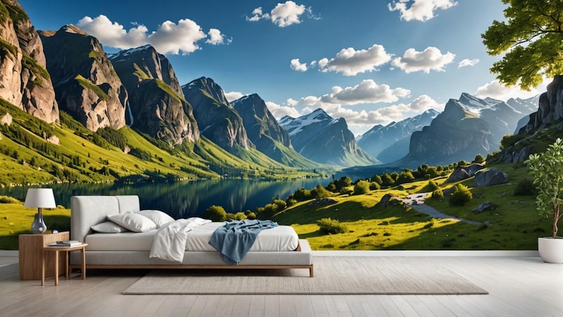 May include: A scenic landscape photograph featuring a lake surrounded by lush green hills and towering mountains. The sky is a bright blue with fluffy white clouds. The sun is shining brightly, casting a warm glow over the scene.
