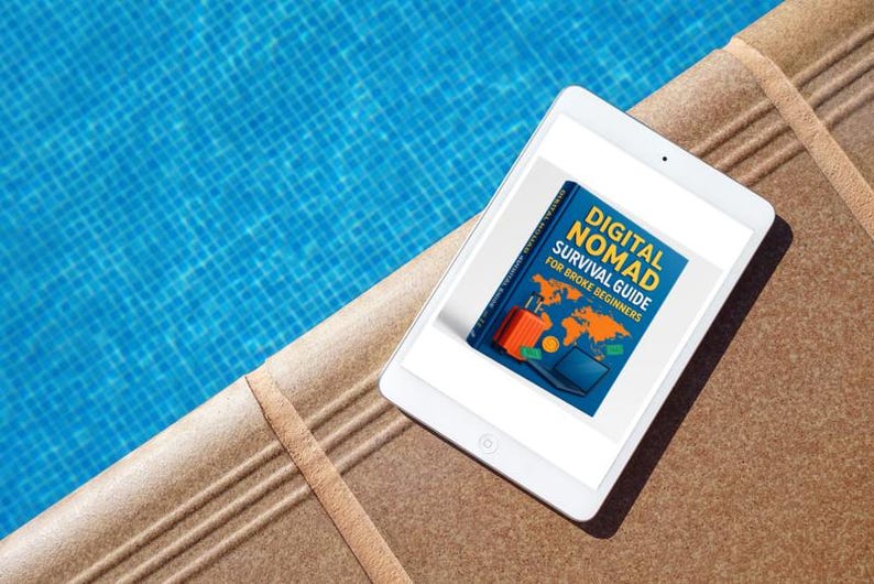 Op de afbeelding: Een witte tablet met de cover van een boek getiteld "DIGITAL NOMAD SURVIVAL GUIDE FOR BROKE BEGINNERS". De cover toont een wereldkaart, een koffer en een laptop. De tablet ligt op een bruin oppervlak naast een blauw zwembad.
