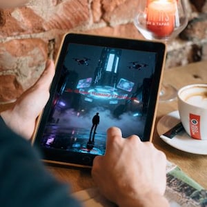 K&ouml;nnte beinhalten: Ein Tablet zeigt eine futuristische Stadtlandschaft mit fliegenden Drohnen und dem Text "The Future of Humanity's Final Hour". Eine brennende Kerze in einem Glas und eine Tasse Kaffee stehen auf dem Tisch.